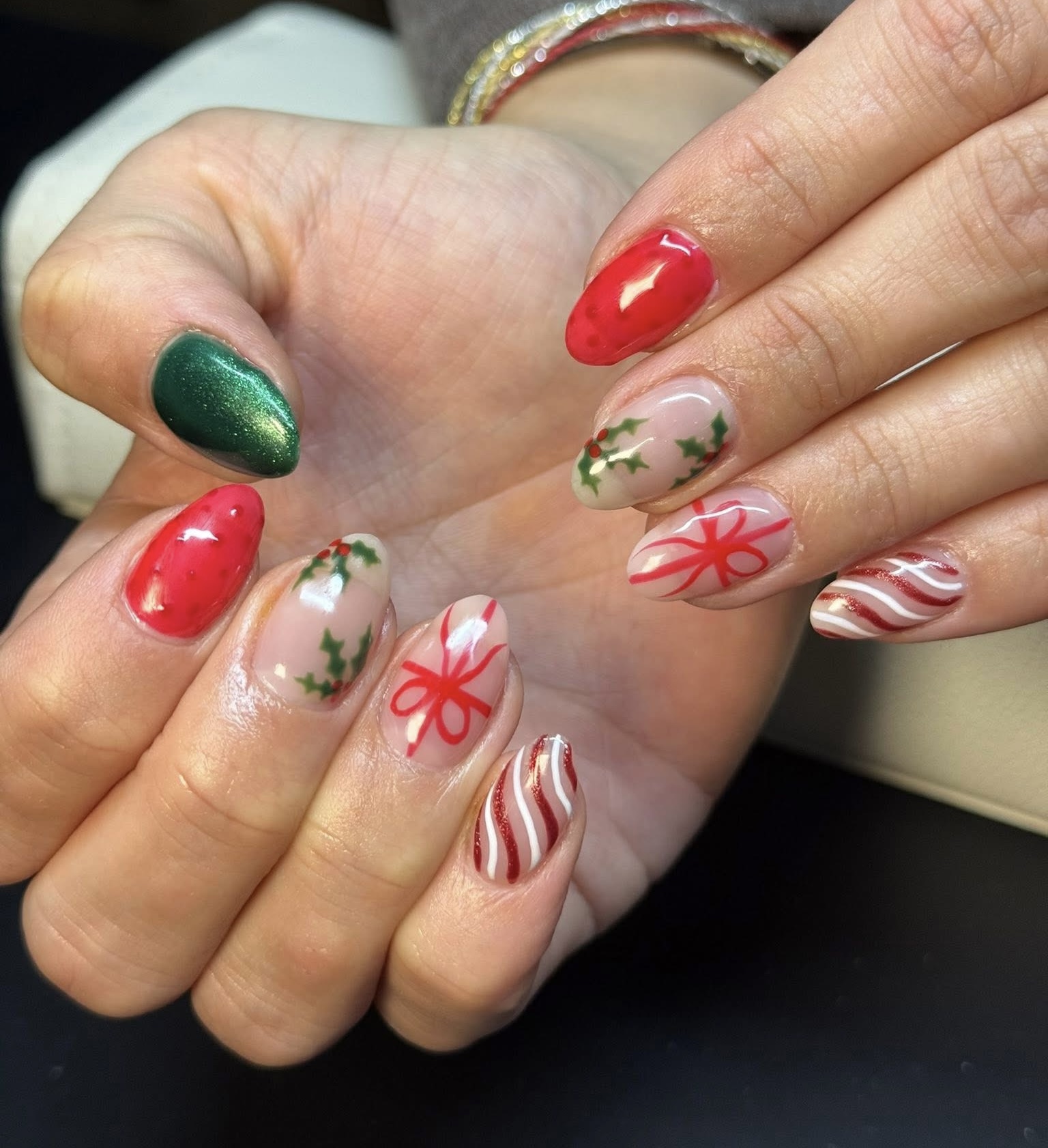Christmas themed nail art with holly, bows, and candy cane stripes