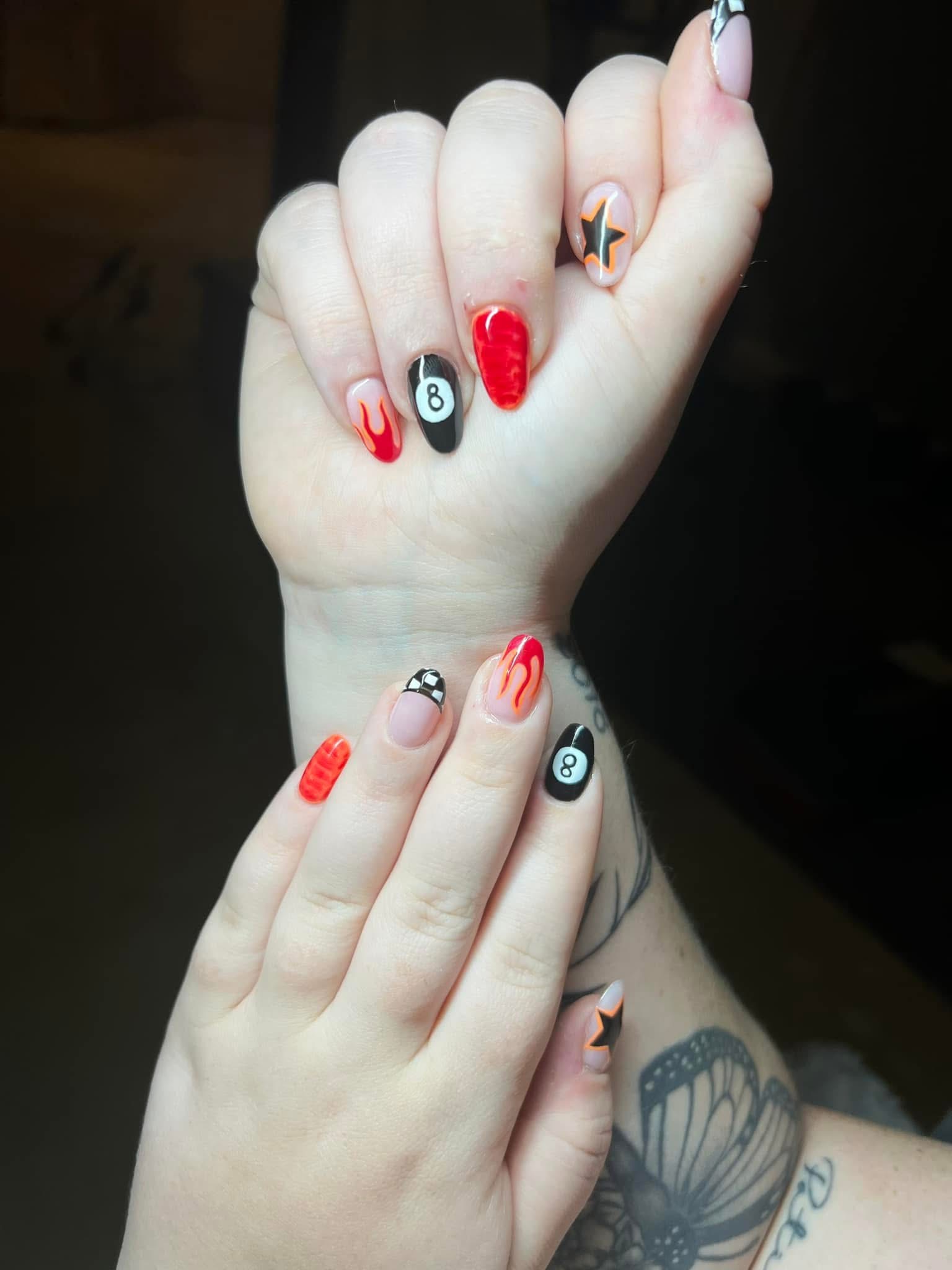 Bold nail art with flames, 8-ball design, and racing flag patterns