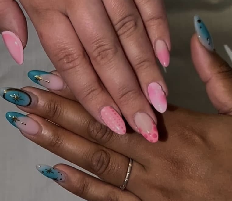 Pink and teal gradient nails with gold starburst designs and silver studs